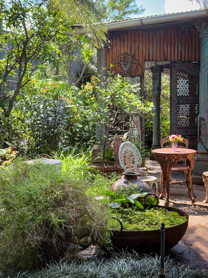 A serene summer garden featuring vintage furniture and lush greenery, ideal for relaxation.