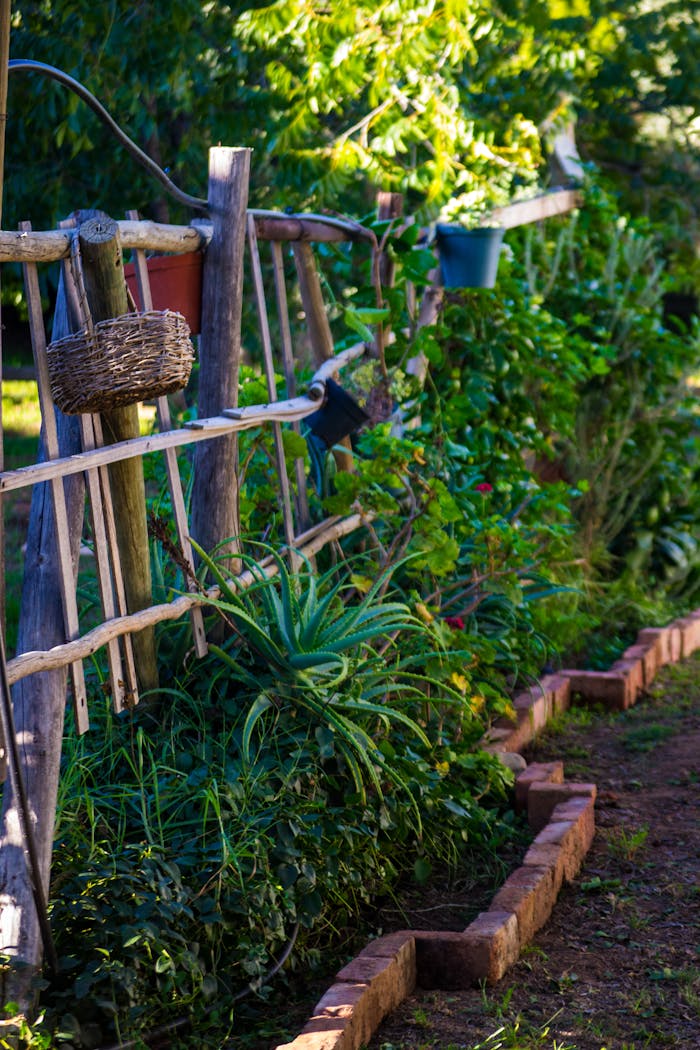A rustic wooden fence in a vibrant garden, adorned with greenery and a brick path.